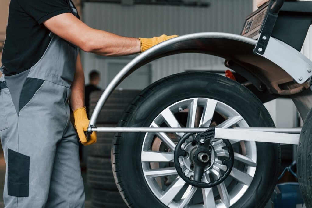 Fixing the tire. Man in uniform is working in the auto service